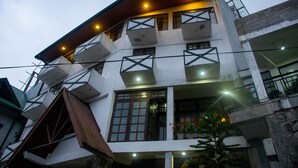 Un immeuble à plusieurs étages doté de balcons, de grandes fenêtres et de plantes d’extérieur.