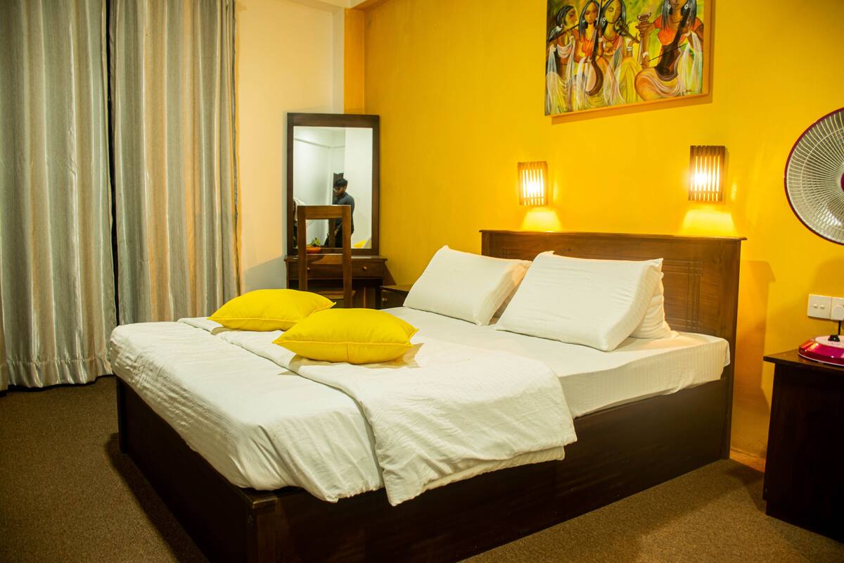 Una habitación de hotel con una cama grande, dos lámparas de noche, una mesita de noche y un cuadro en la pared.
