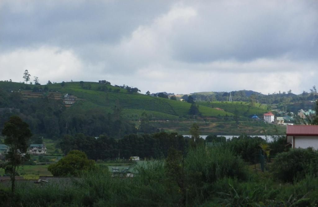 A rural landscape with rolling hills, a body of water, and scattered buildings.