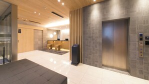 A modern lobby with a reception desk, a waiting area, and an elevator. - Just Inn Premium Nagoya Station (Nagoya)
