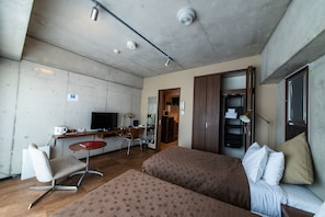 Habitación de hotel con dos camas, un escritorio, una silla, un televisor y un armario.