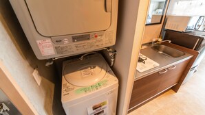 Cocina compacta con lavadora y secadora integradas, un lavamanos y un espejo sobre la encimera.