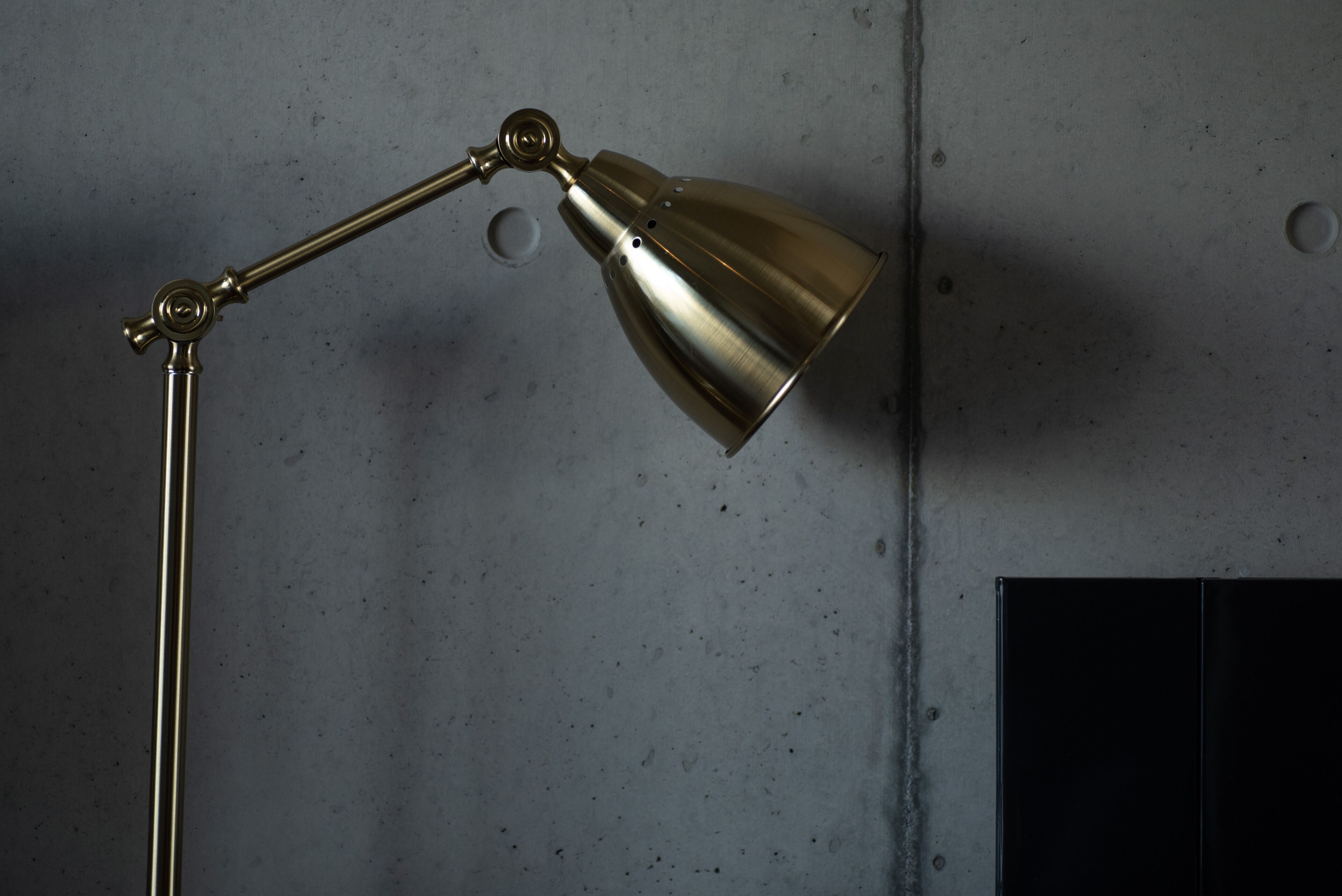 Een metalen bureaulamp met een gebogen arm en een conische kap, bevestigd aan een muur.