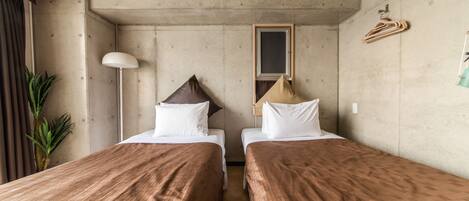 A room with two beds, a hanging light, a mirror, and a plant.