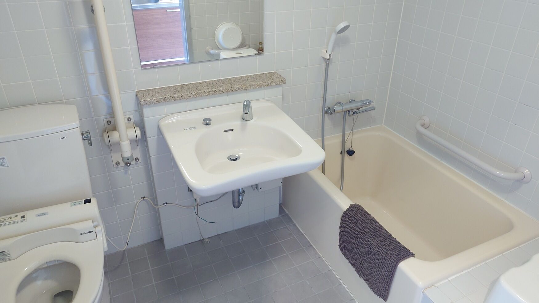 A bathroom with a white sink, toilet, and bathtub, with a mirror above the sink and a towel rack beside the bathtub.