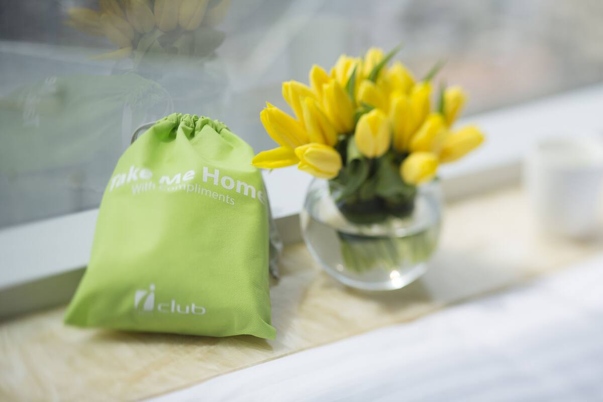 A green drawstring bag with text and a vase of yellow tulips on a table.
