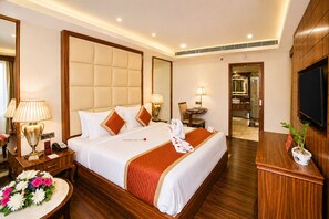 A hotel room with a large bed, bedside tables, a TV, and a bathroom visible through an open door. - Shakun Hotels & Resorts Jaipur (Jaipur)