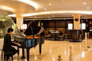 A grand piano in a spacious lobby with a seating area and a dining section in the background. - Shakun Hotels & Resorts Jaipur (Jaipur)