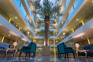 A multi-level atrium with a central palm tree, seating areas, and a modern design.
