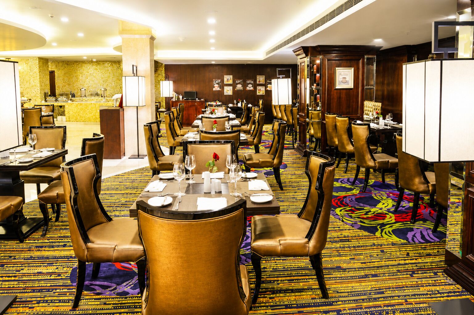 A hotel dining area with round tables, chairs, and a buffet counter.