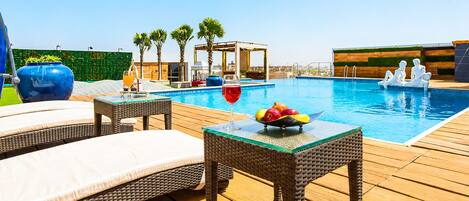 A poolside area with lounge chairs, a table with fruit, and a decorative sculpture.