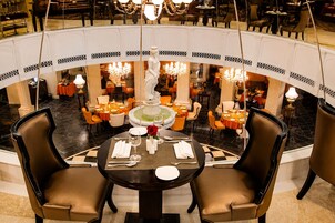 Um restaurante com mesas redondas, cadeiras e uma fonte central.