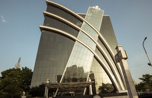 A modern hotel with a curved glass facade and a prominent entrance canopy.