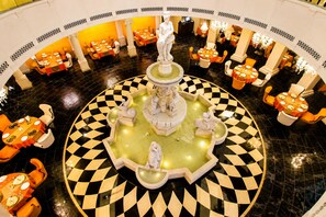 A hotel lobby with a central fountain, multiple dining tables, and a checkered floor pattern. - Shakun Hotels & Resorts Jaipur (Jaipur)