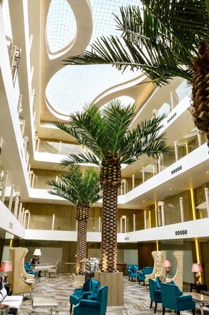 A multi-level atrium with palm trees, seating areas, and a modern architectural design. - Shakun Hotels & Resorts Jaipur (Jaipur)