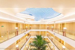 A multi-level hotel lobby with a central atrium, glass railings, and a patterned floor. - Shakun Hotels & Resorts Jaipur (Jaipur)