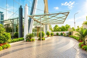 A modern building with a glass entrance and a curved pathway lined with potted plants. - Shakun Hotels & Resorts Jaipur (Jaipur)