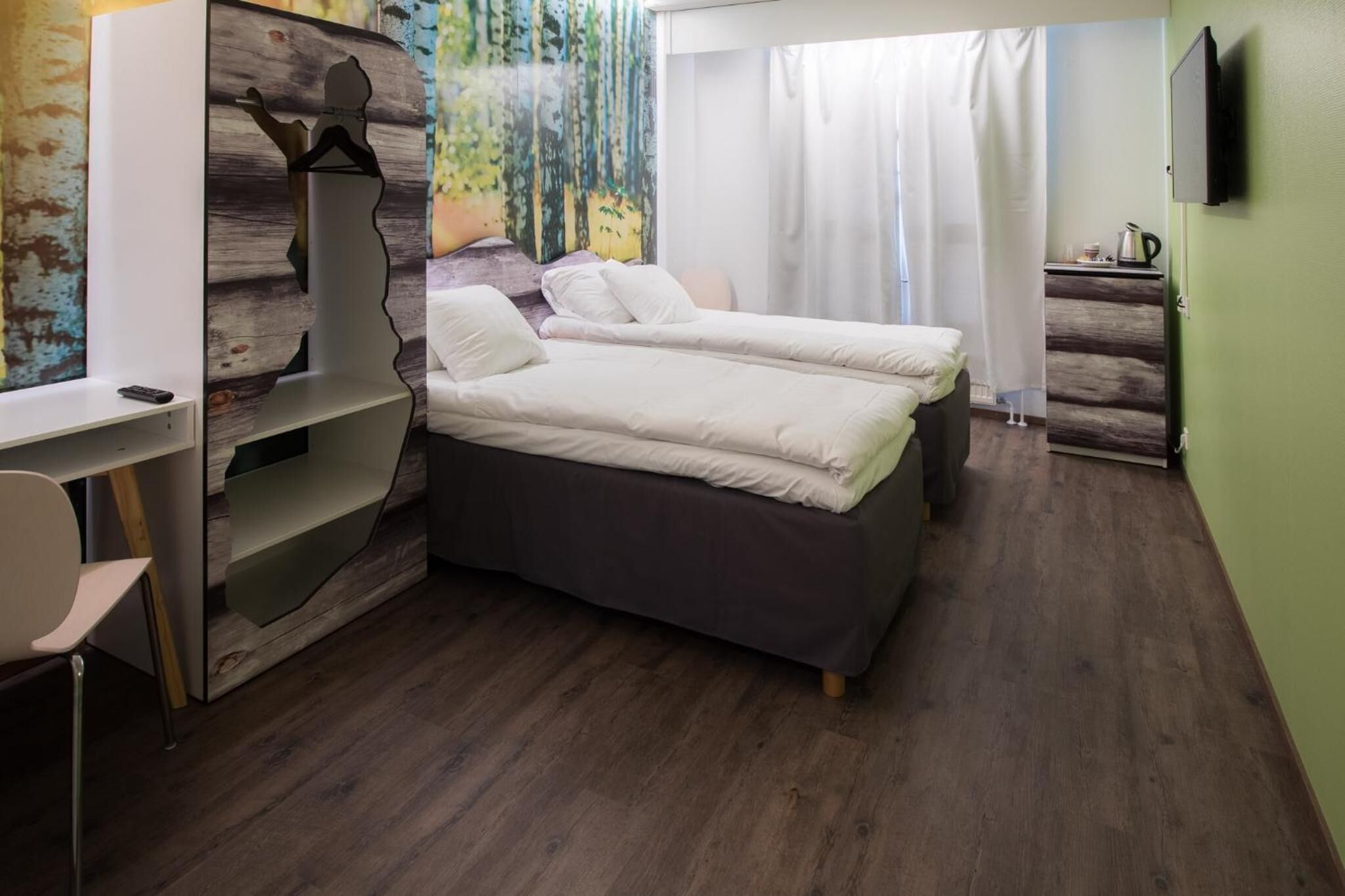 A bedroom with two beds, a desk, and a TV.