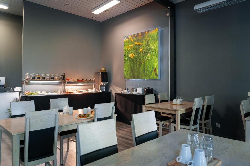 A dining area with tables and chairs, a buffet with food and drinks, and a large painting on the wall.