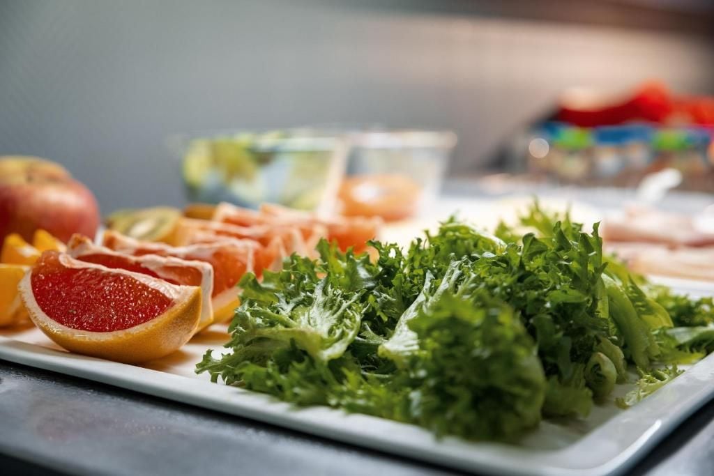 A plate with various fresh fruits and vegetables, including grapefruit and leafy greens.