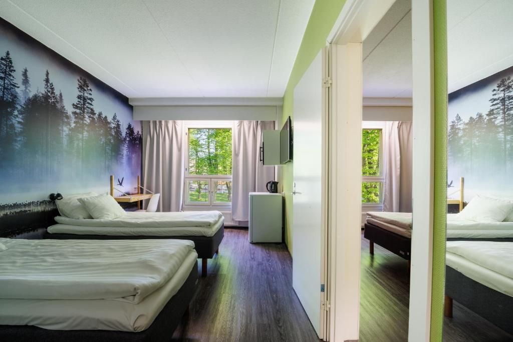 A hotel room with two beds, a desk, a small refrigerator, and a TV.