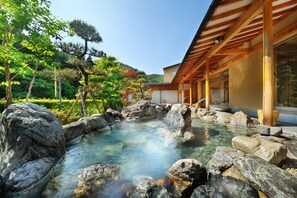 Uma onsen japonesa tradicional com estrutura de madeira e uma fonte termal cristalina rodeada por pedras.