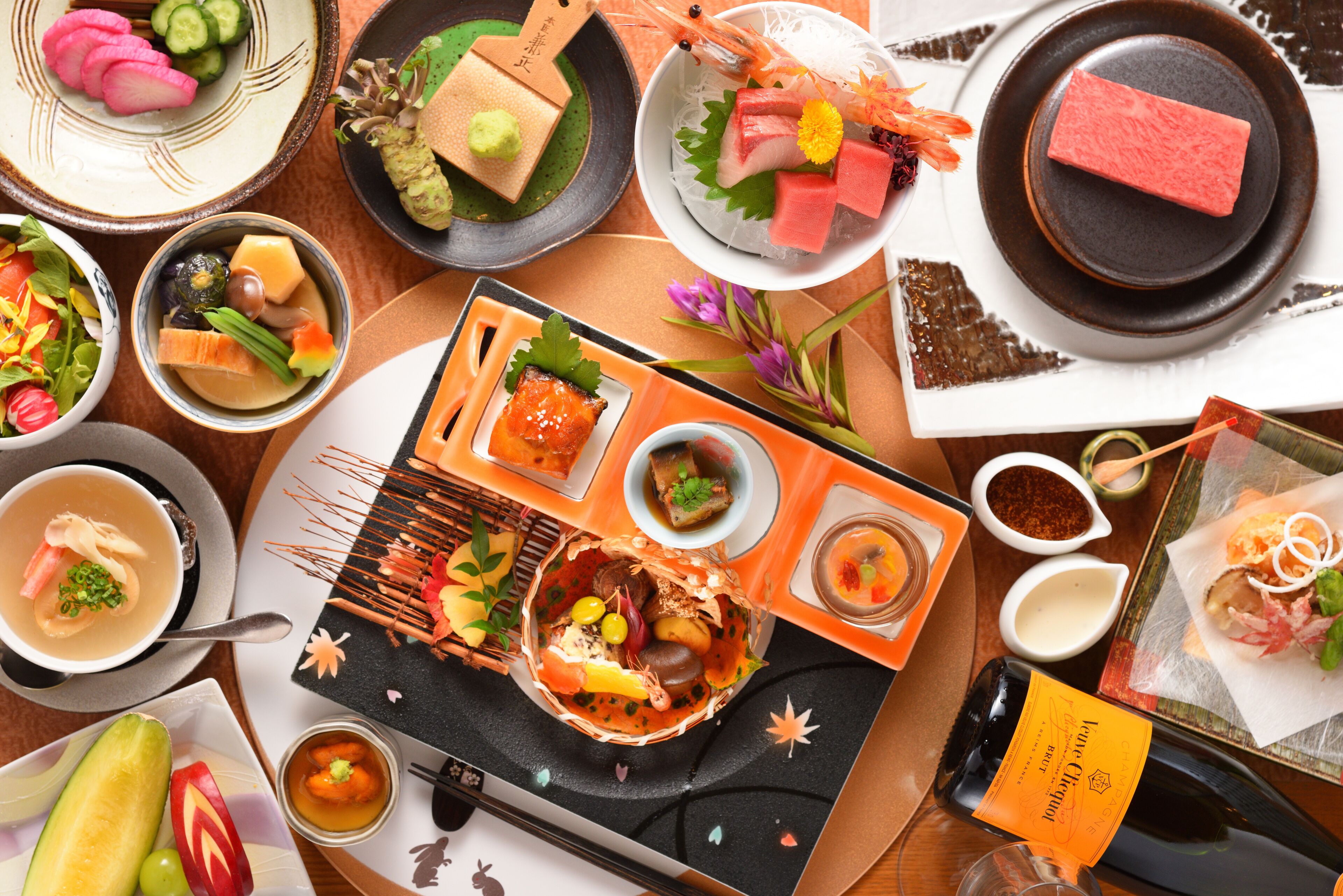 A variety of Japanese dishes including sushi, sashimi, and tempura, arranged on a wooden table.