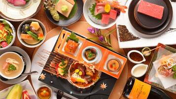 A variety of Japanese dishes including sushi, sashimi, and tempura, arranged on a wooden table.