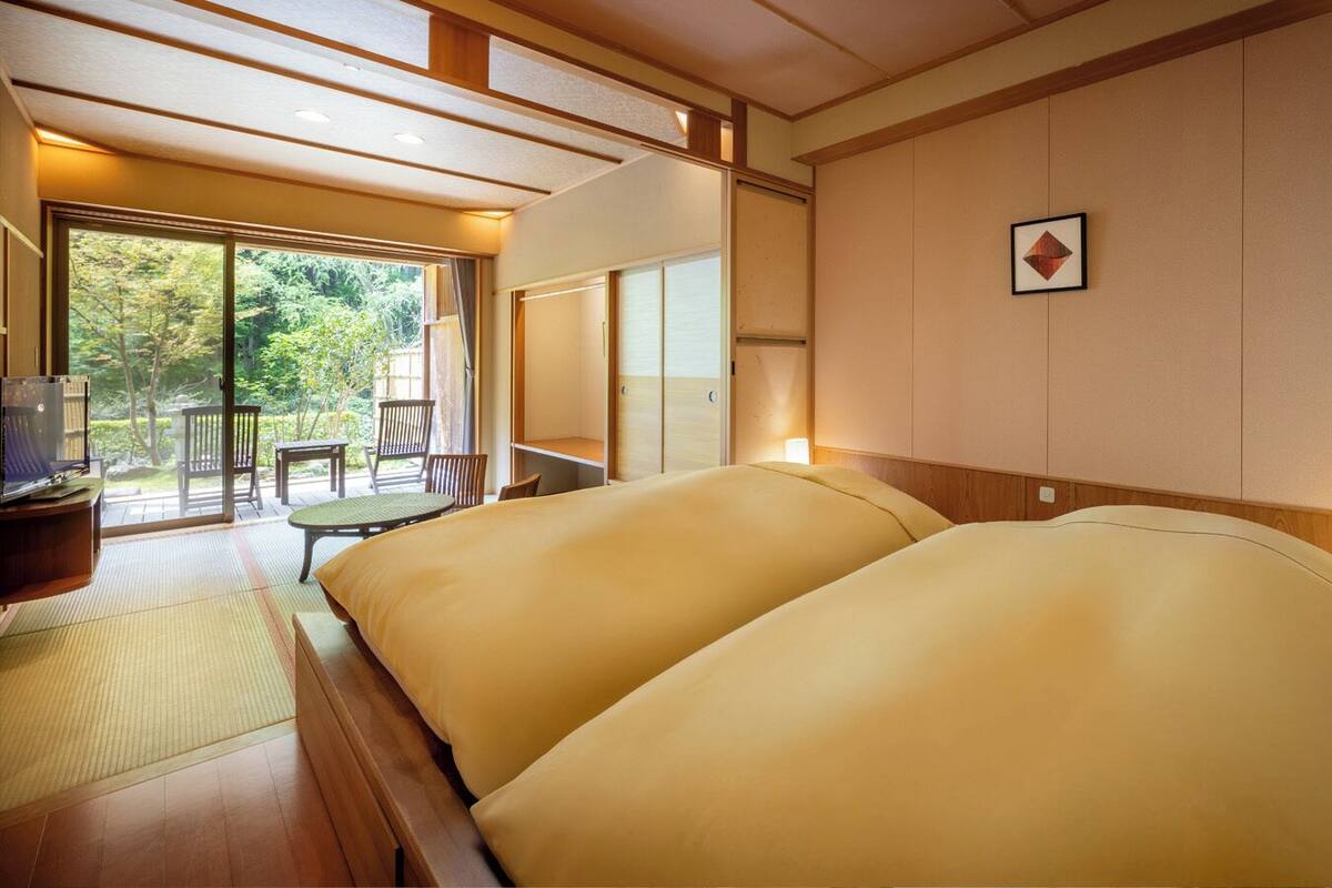 A traditional Japanese-style room with tatami flooring, a low wooden bed, and a sliding door leading to a balcony.