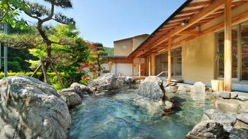 A traditional Japanese-style building with a wooden structure and a clear water feature with rocks.