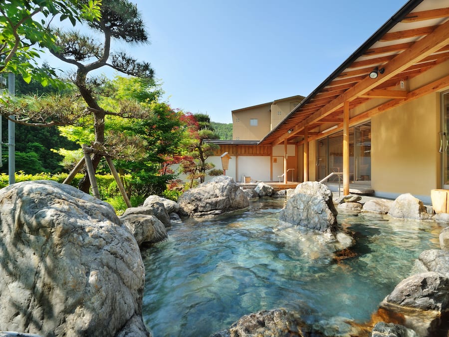 Un edificio tradicional japonés con estructura de madera y una fuente de agua cristalina con rocas.