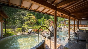 A hot spring area with wooden beams, a stone pathway, and a view of a forest.