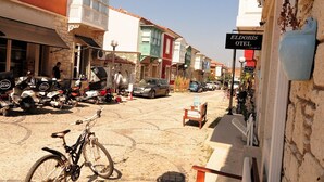 Una calle con motocicletas estacionadas y una bicicleta, un letrero que dice 'Eldoris Hotel' y un edificio con fachada de piedra.