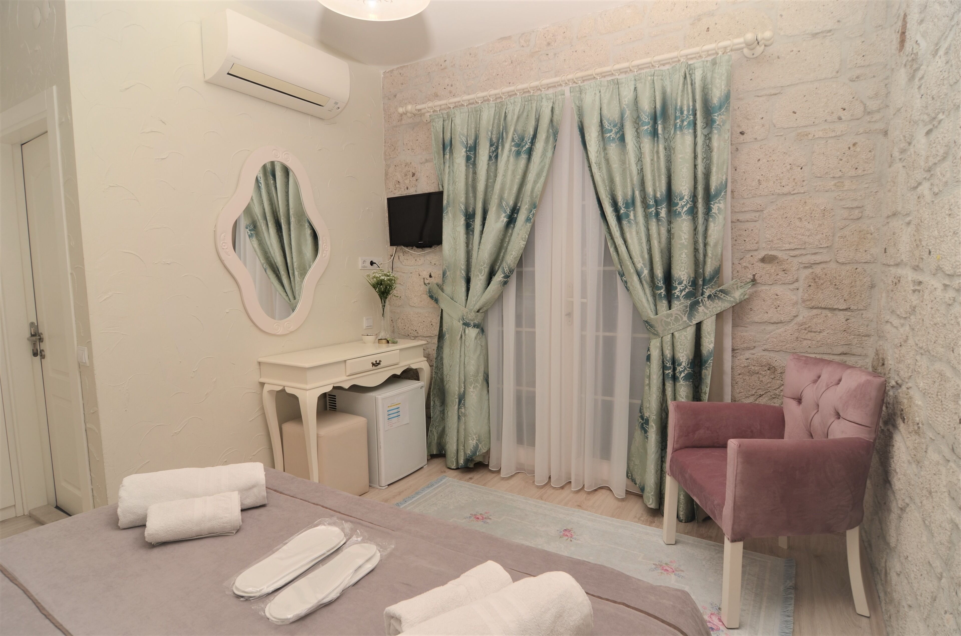 Une pièce comprenant un lit, une chaise, une coiffeuse avec un miroir, une petite table et un téléviseur.