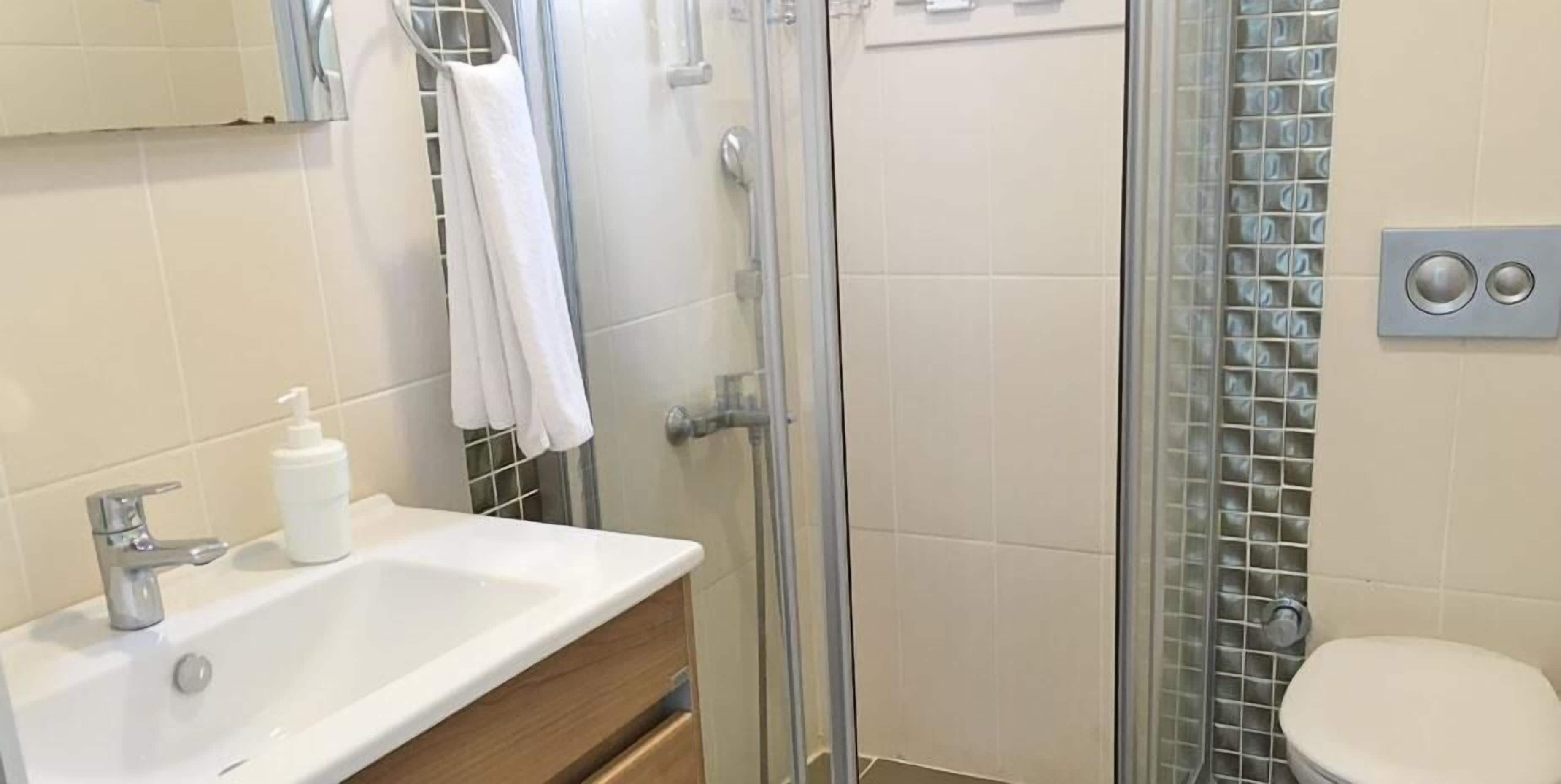 Een badkamer met een wastafel, een douchecabine van glas en een toilet.