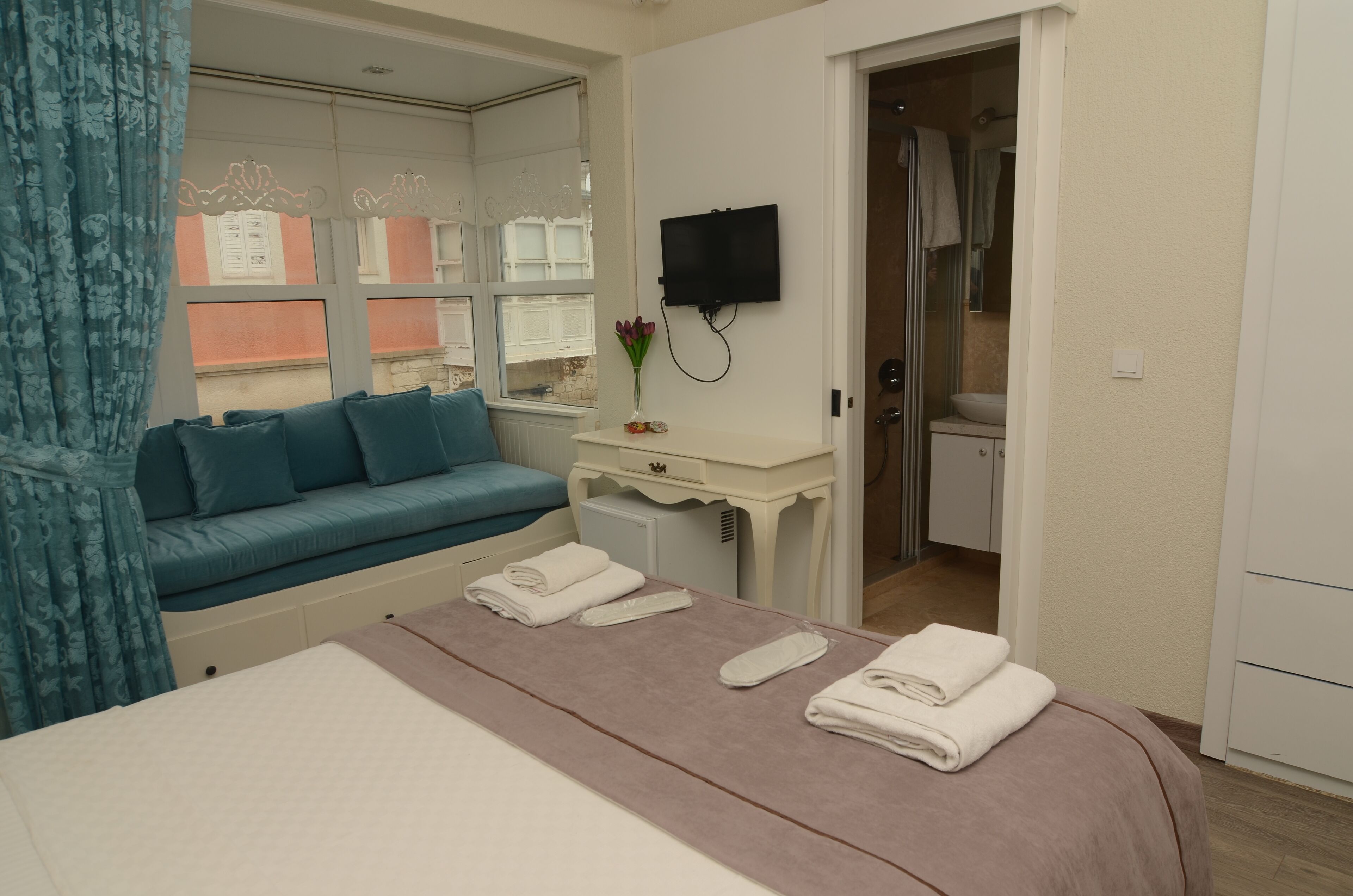 Een hotelkamer met een bed, een klein bureau, een televisie en een badkamer door een open deur zichtbaar.