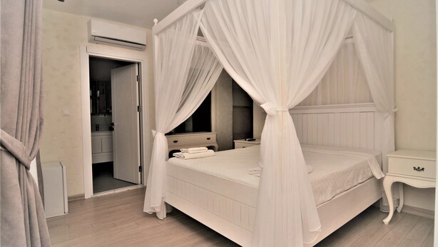 Un dormitorio con cama con dosel, mesita de noche y armario.