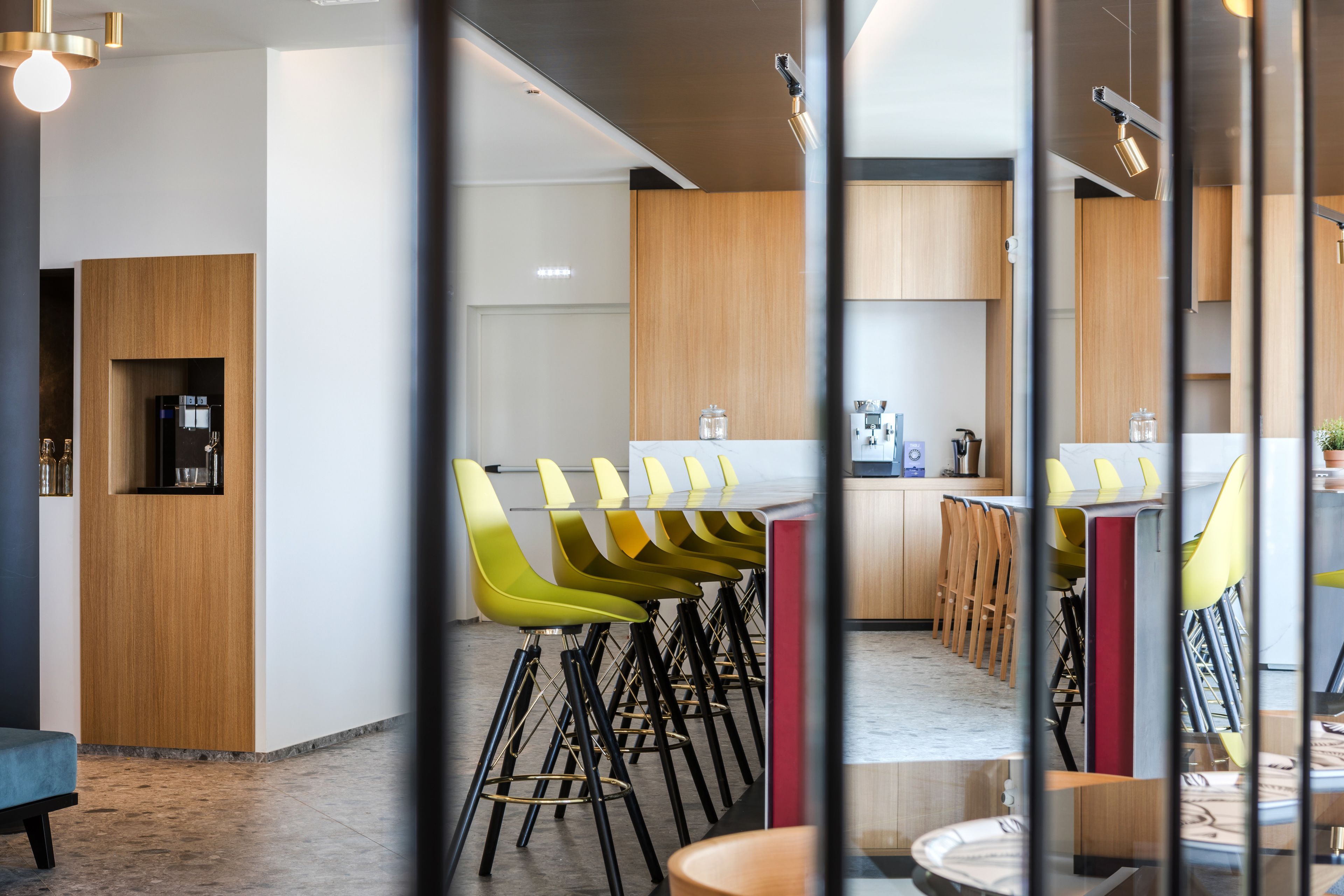 Una cocina moderna con armarios de madera, una isla central y una zona de estar con sillas.