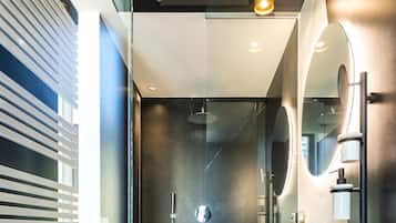 A modern bathroom with a glass partition, a black sink, and a mirror.