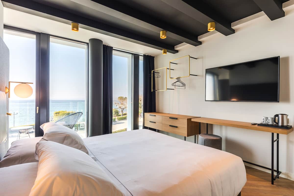 A modern bedroom with a large bed, a desk, and a TV.