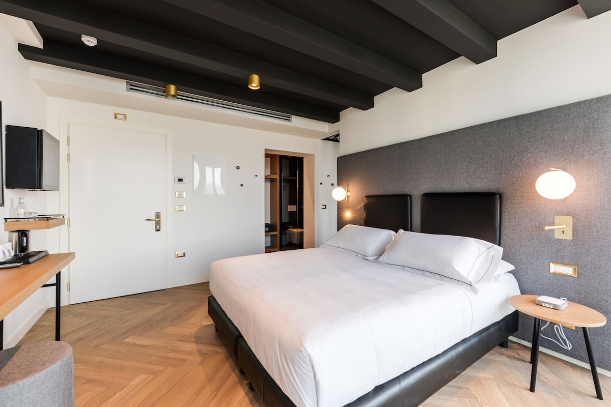 A modern bedroom with a large bed, bedside tables, a desk, and a wardrobe.