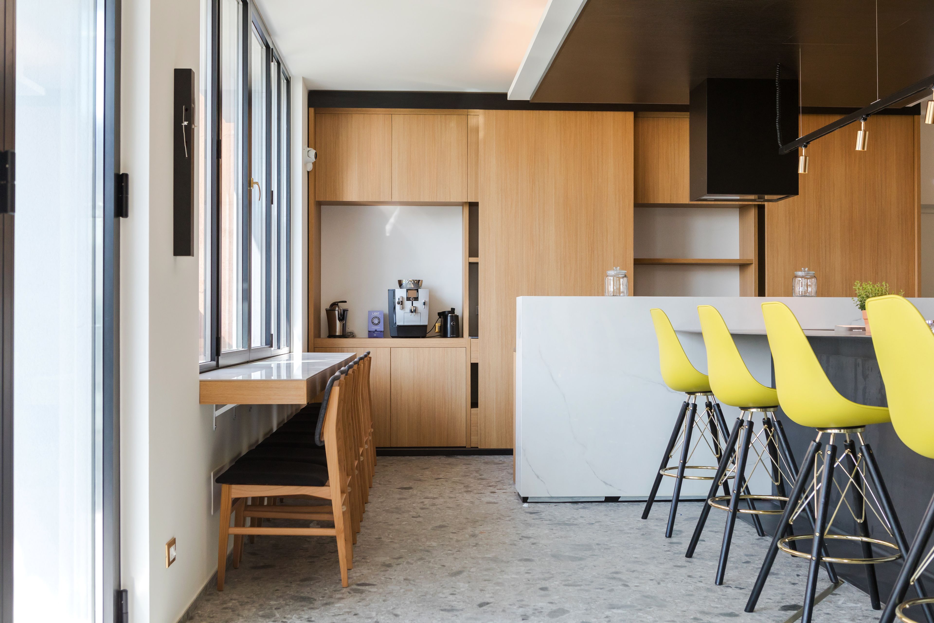A modern kitchen with wooden cabinets, a white marble countertop, and a built-in TV.