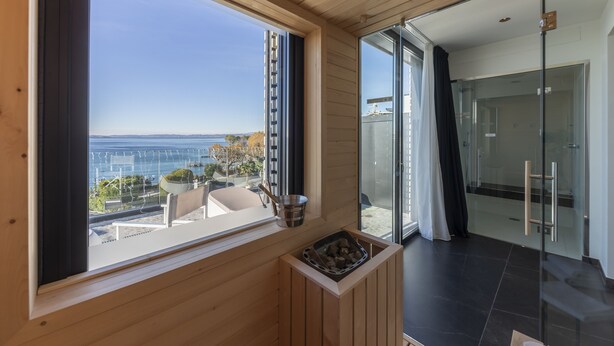 Een moderne kamer met een groot raam met uitzicht op een mooi landschap, een zithoekje en een glazen deur naar buiten.