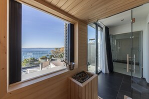 Une chambre moderne dotée d’une grande fenêtre donnant sur un paysage magnifique, d’un petit coin salon et d’une porte vitrée qui mène à un espace extérieur.