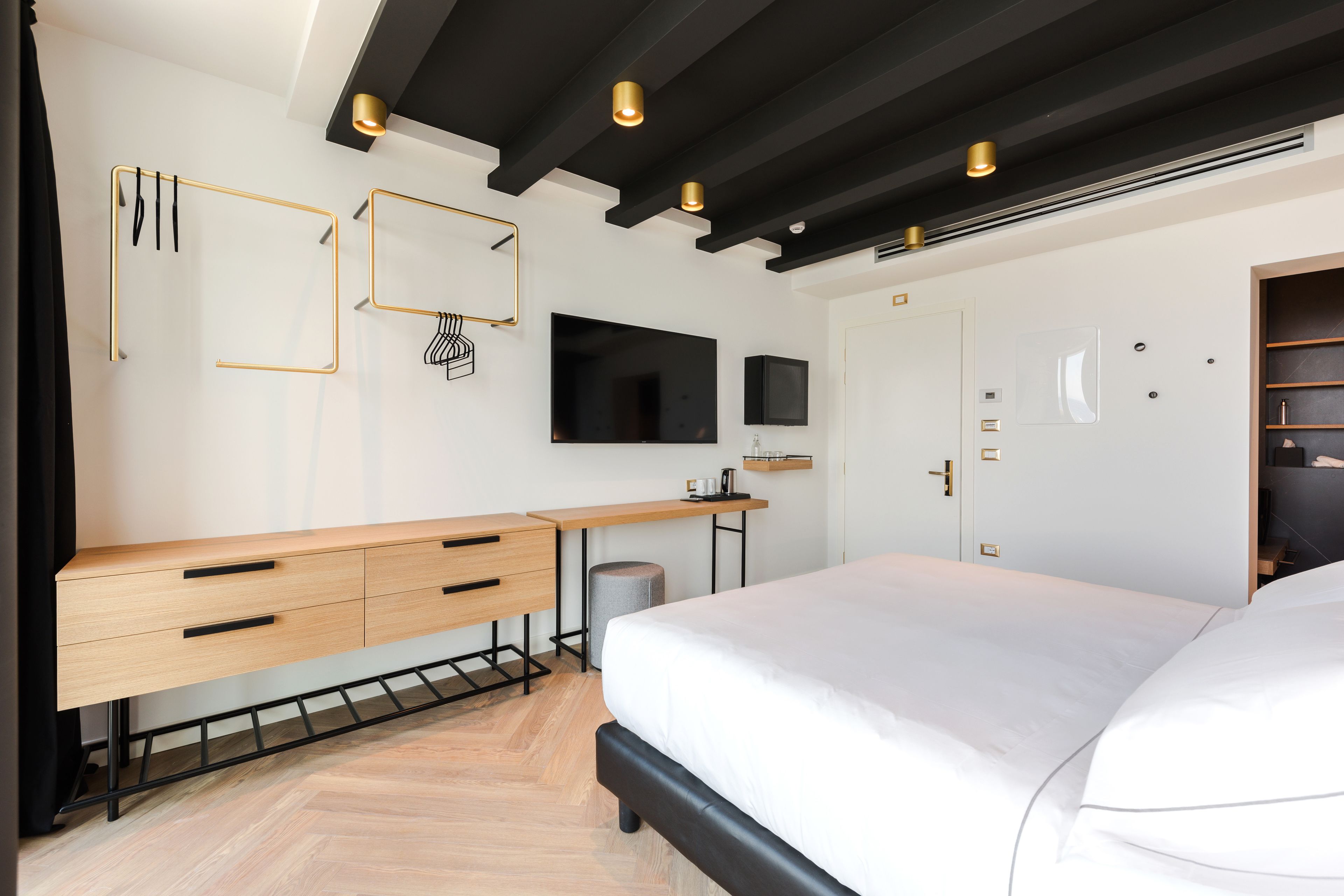 A modern bedroom with a bed, a desk, and a TV.
