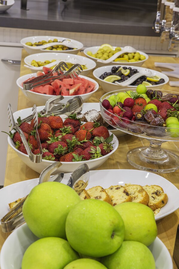 A buffet table with various fruits and desserts.