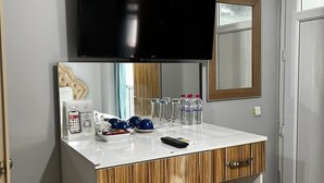 A hotel room with a wooden vanity, a flat-screen TV, a minibar, and a mirror. - In Vivo Hotel (Izmir)