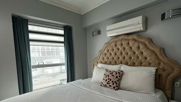 A hotel room with a large bed, a window with curtains, an air conditioning unit, and a bedside table. - In Vivo Hotel (Izmir)