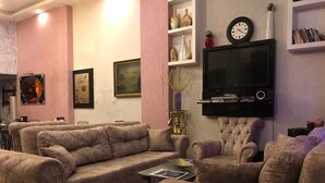 A living room with a sofa set, a television mounted on the wall, and decorative items on shelves. - In Vivo Hotel (Izmir)