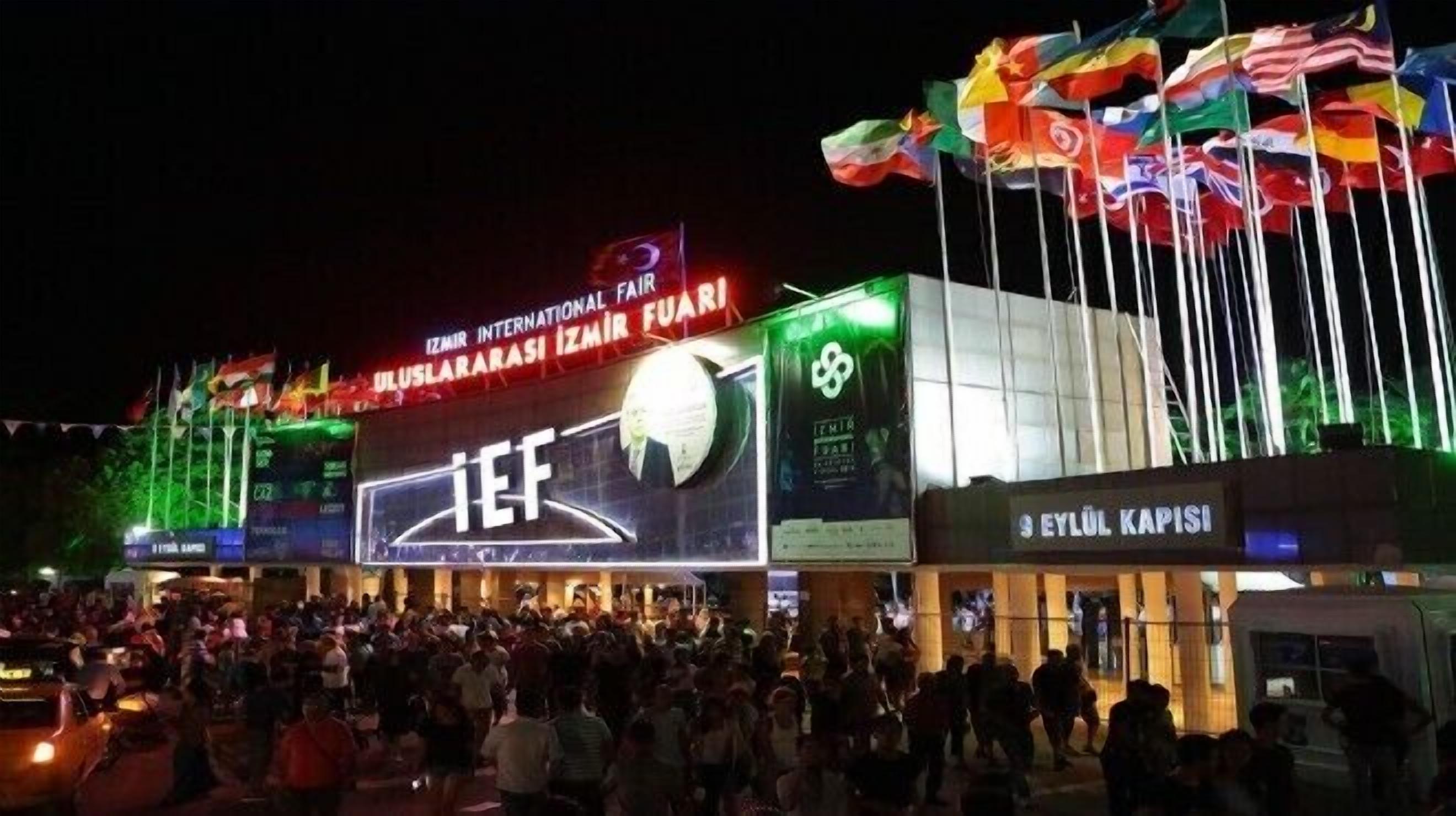 A building with multiple flags and a large crowd in front.